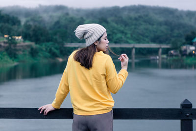 A woman wearing a yellow sweater on a wooden bridge