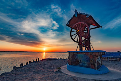 Lifeguard hut on beach against sky during sunset