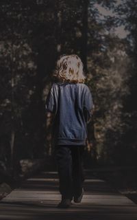 Rear view of boy standing against trees