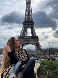 Young woman sitting against eiffel tower 