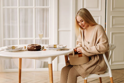 Young woman sitting on table at home