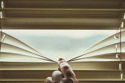 Cropped hand of person holding window covering