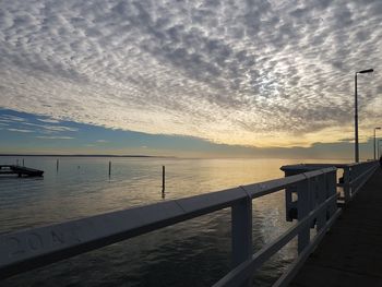 Pier over sea against sky during sunset