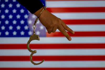 Cropped hand with handcuffs showing peace sign against american flag