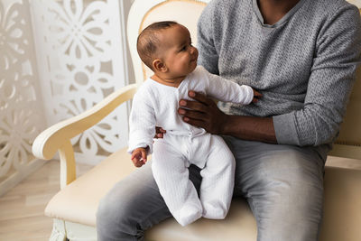 Rear view of father and daughter sitting at home