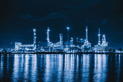 Illuminated factory against sky at night