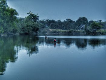 Man on boat in lake against sky