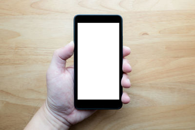 Close-up of hand holding mobile phone on table