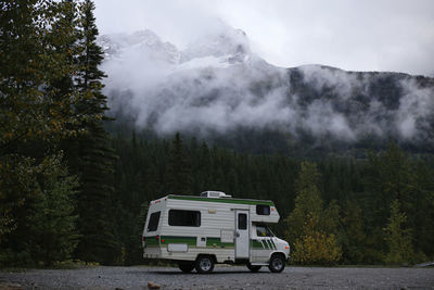 Motor home on road against trees and mountain during foggy weather