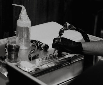 Cropped hand of tattoo artist holding work tool in workshop