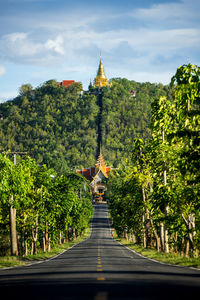 Walkway amidst trees and building against sky