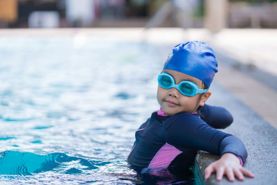 Happy children smiling cute little girl in sunglasses in swimming pool.