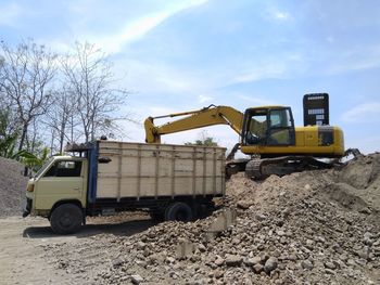 Cars on road by construction site against sky