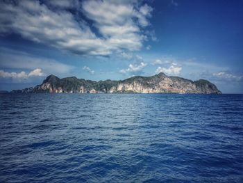 Scenic view of sea against sky with small rock formation on horizon