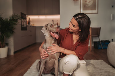 Portrait of young woman with dog at home