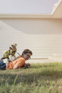 Boy playing with yorkshire terrier on grassy field at backyard