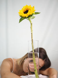 Close-up of woman holding yellow flower in glass