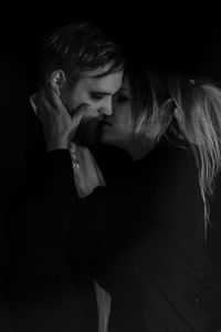 Couple kissing against black background