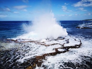 Scenic view of sea waves splashing on shore against sky