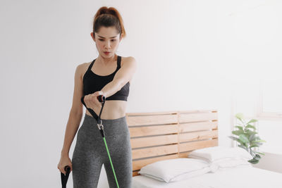 Young woman looking away while standing against wall