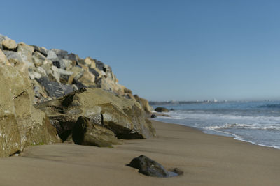 Surface level of rocks on beach against clear sky