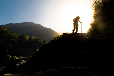 Low angle view of silhouette woman hiking on mountain against sky