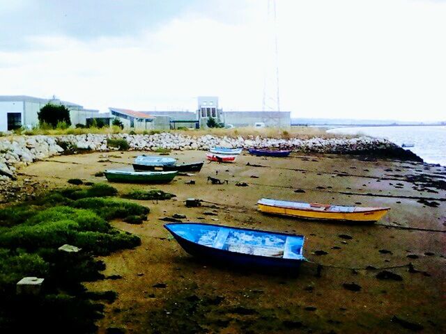 BOATS MOORED AT BEACH AGAINST SKY