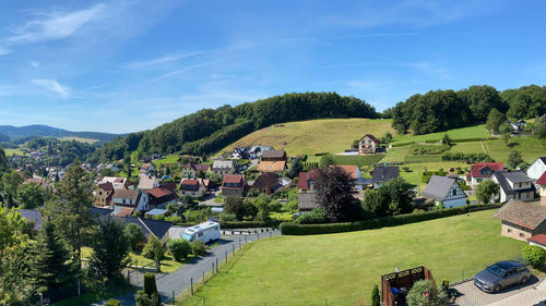 Houses and trees on field against sky