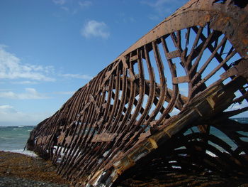 Metallic structure on beach against sky