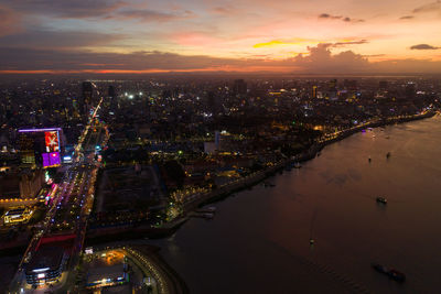 Aerial view of illuminated buildings in city at sunset