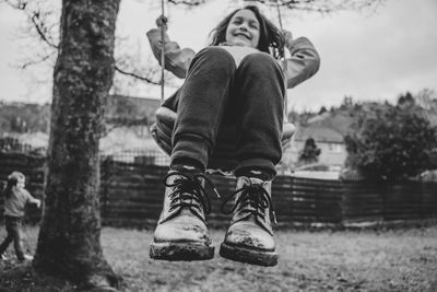 Low wide angle view of a girl on a swing in a rural neighborhood