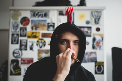 Portrait of young man smoking against stickers wall