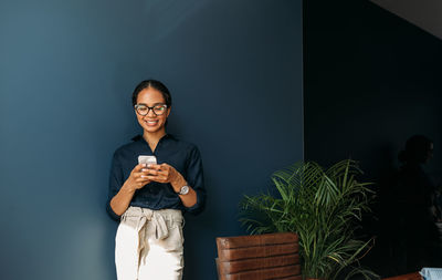 Portrait of young woman standing against wall