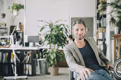 Portrait of confident creative businessman sitting on chair in office