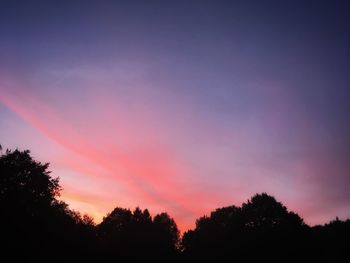 Low angle view of silhouette trees against romantic sky