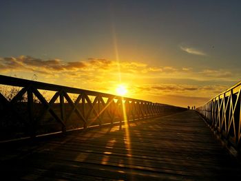 Footbridge against sky during sunset