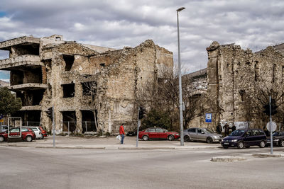 Road by buildings in city against sky