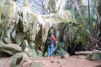 Rear view of woman standing against cave