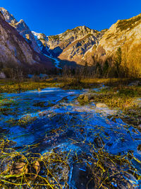 Scenic view of lake by mountains against clear blue sky