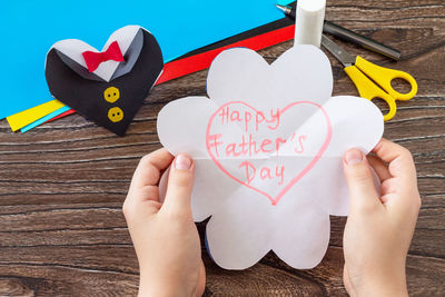 Midsection of woman holding heart shape text on paper