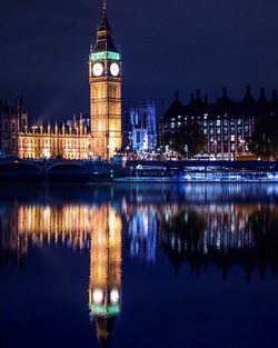 Illuminated big ben by thames river at night