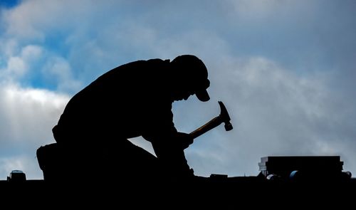 Low angle view of silhouette man standing against sky