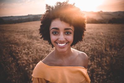 Portrait of smiling young woman standing on field