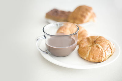 Coffee cup with croissants on table against white background