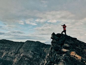 Low angle view of woman standing on mountain against sky