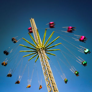 Low angle view of chain swing ride against sky