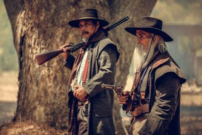 Men holding weapons while standing outdoors