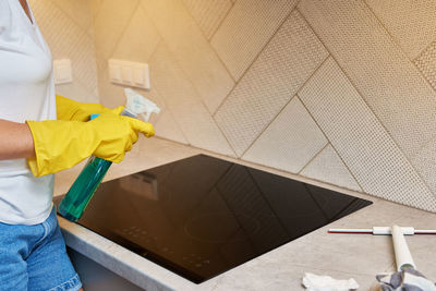 Woman in rubber gloves cleaning induction stove