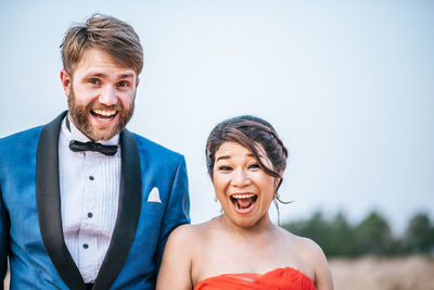 Portrait of cheerful couple standing against sky