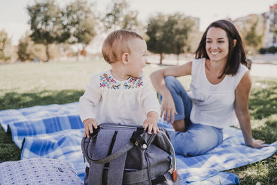 Mother and daughter sitting on picnic blanket at park